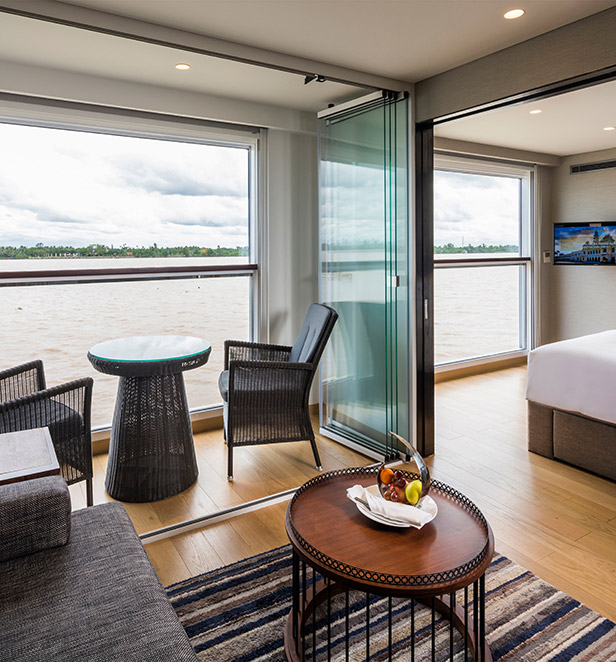 The lounge area and Scenic Sun Lounge in the Grand Deluxe Suite, surrounded by floor-to-ceiling windows that offer views of the river beyond.