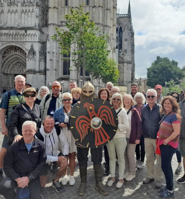 Group of tourists posing with a Viking reenactor in front of a cathedral in Rouen