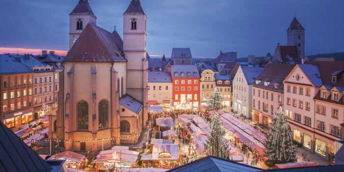 Festive Christmas market in Regensburg, Germany with decorated stalls and historic buildings at dusk