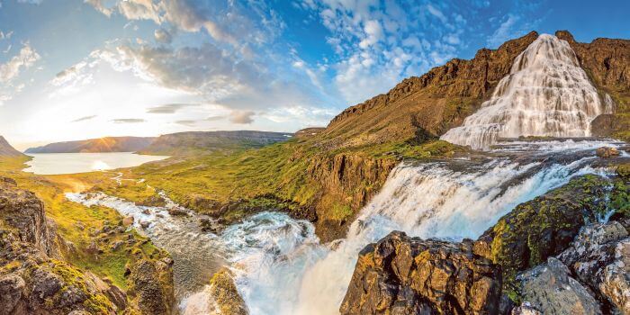 Dynjandi Waterfall cascading down rocky cliffs in Iceland at sunset