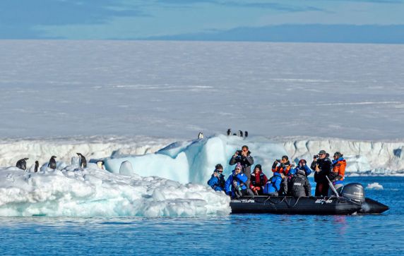 Guests in a Scenic Eclipse Zodiac observing penguins on an iceberg in Antarctica