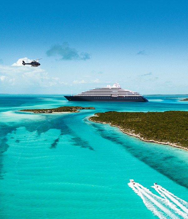 Scenic Eclipse in the Bahamas with a helicopter flying above it
